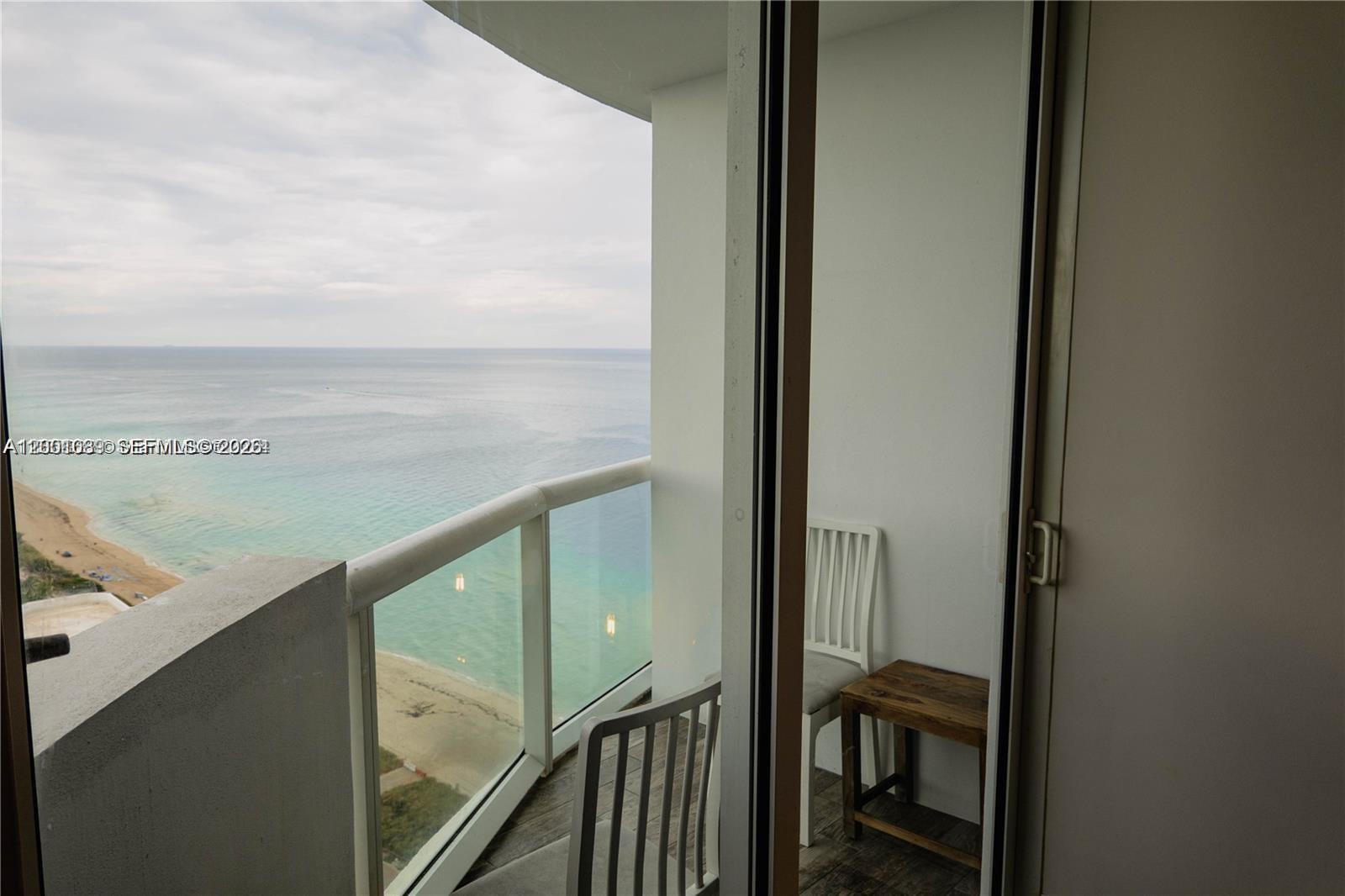 A balcony with a glass railing overlooks the ocean and a sandy beach — 6365 Collins Ave # 2710, Miami Beach FL 33141, MIAMI BEACH, FL