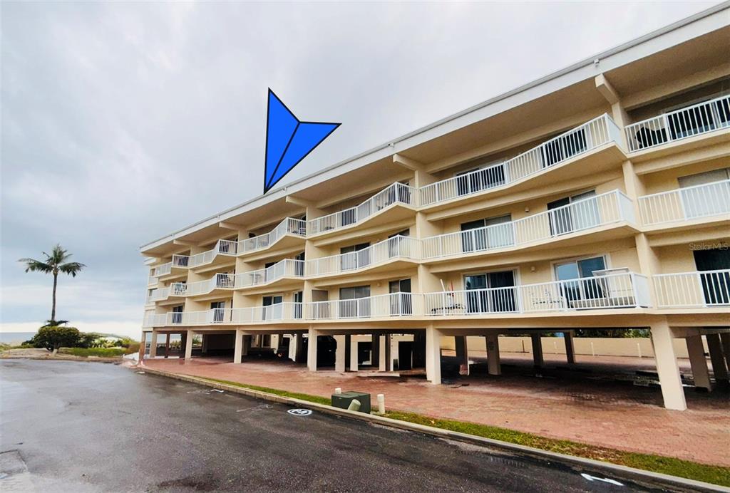 A multi-story apartment building with elevated parking and balconies overlooking a paved area — 1480 GULF BOULEVARD UNIT 304, ENGLEWOOD, FL