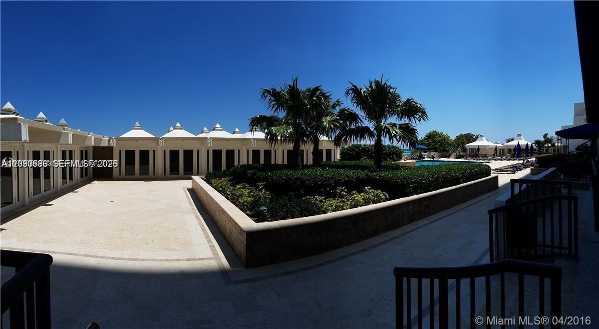 A paved courtyard features a central garden bed with palm trees and surrounding building structures — 5555 Collins ave # 9V, Miami Beach FL 33140, MIAMI BEACH, FL