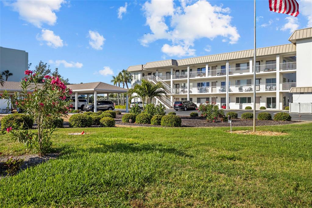 A living room features wood-paneled walls, a large mirror, a glass coffee table, and patio access — 3330 GULF OF MEXICO DRIVE UNIT 107D, LONGBOAT KEY, FL