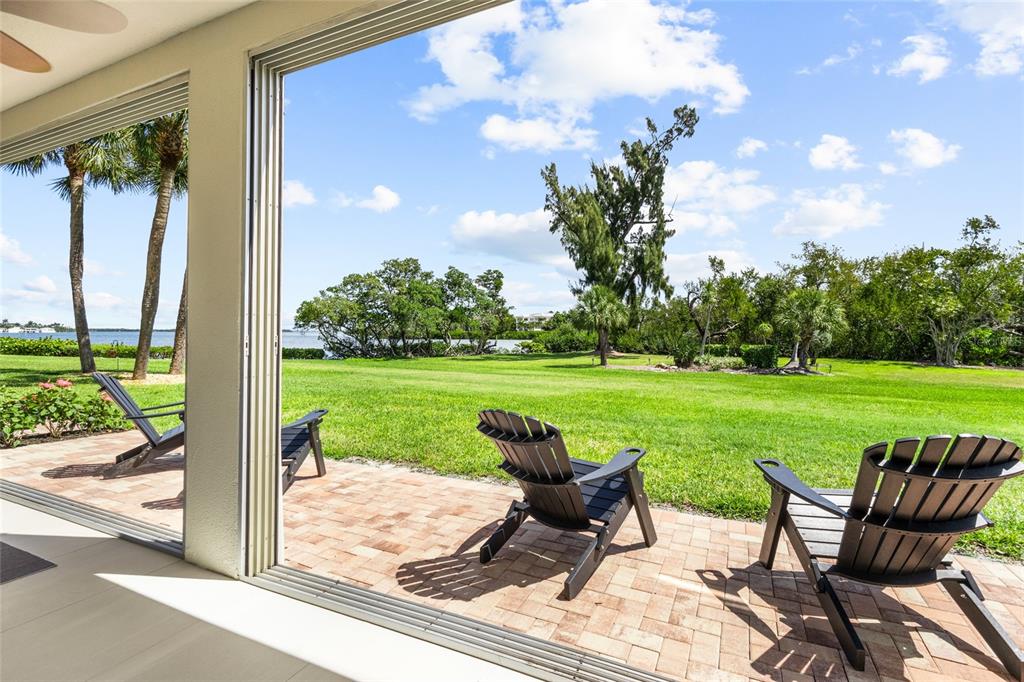A modern open-concept living and dining area features a dark table, leather chairs, and sliding doors — 3330 GULF OF MEXICO DRIVE UNIT 107D, LONGBOAT KEY, FL
