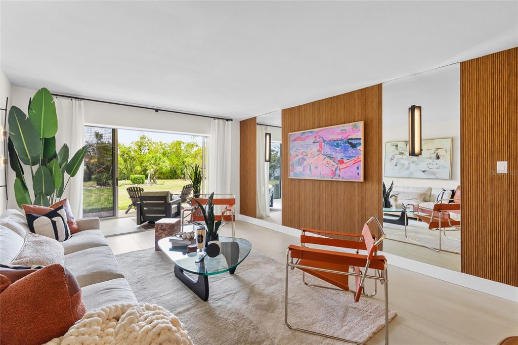 A bright living room features a beige sofa, two leather chairs, and a sliding glass door — 3330 GULF OF MEXICO DRIVE UNIT 107D, LONGBOAT KEY, FL