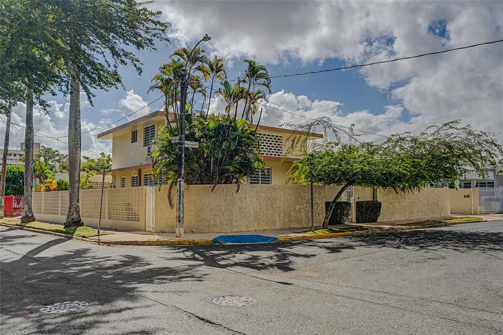 A two-story yellow house with a concrete perimeter wall sits on a street corner — 901 HARVARD, SAN JUAN, PR