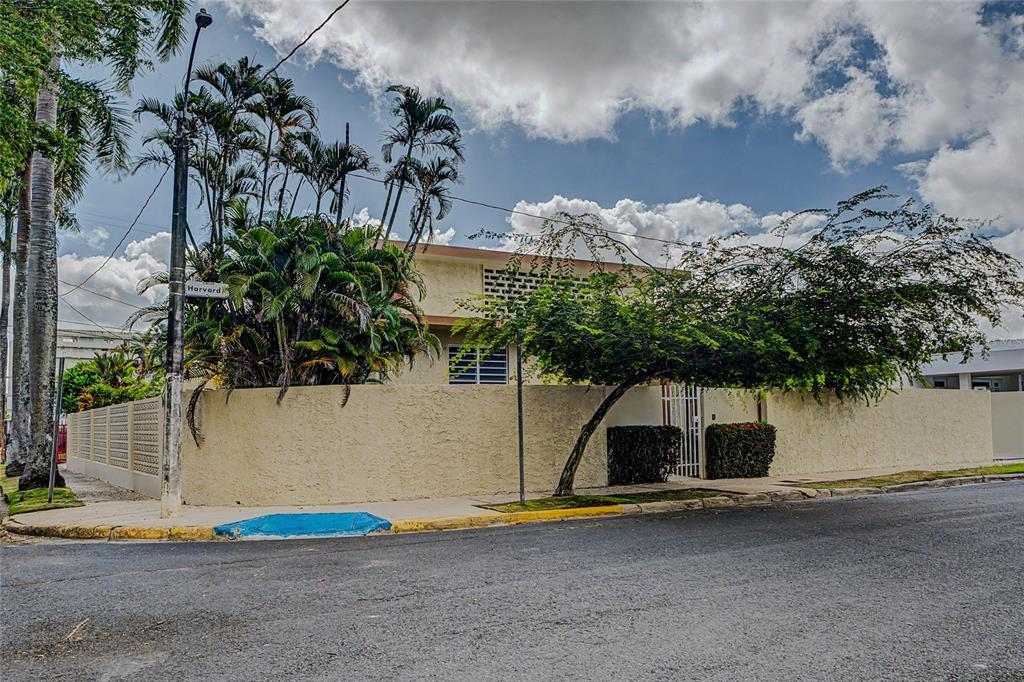 A beige stucco house with a privacy wall and palm trees sits on a corner — 901 HARVARD, SAN JUAN, PR