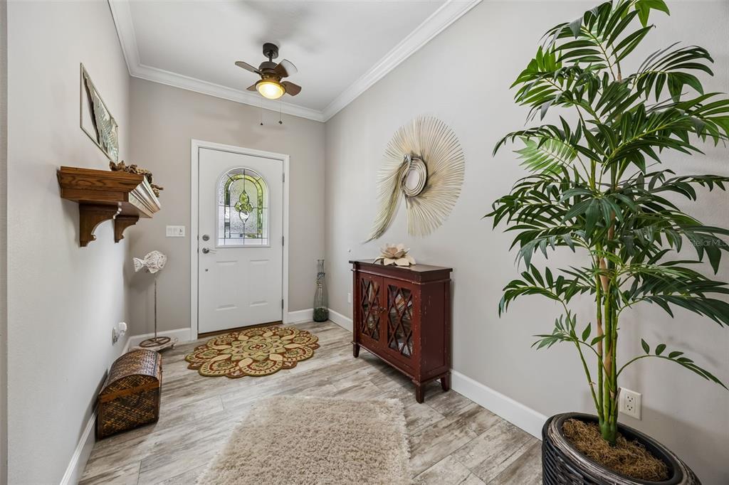 An entryway features light wood-look flooring, a white front door, a ceiling fan, and decor — 329 PARADISE CIRCLE, SATSUMA, FL