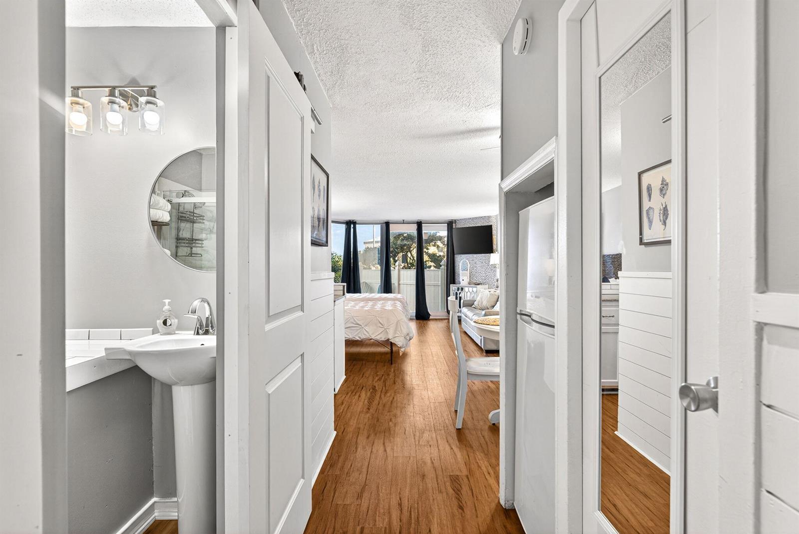A hallway leads from a bathroom into a bedroom and living area with wood flooring — 8817 S Thomas Drive # A114, Panama City FL 32408, PANAMA CITY, FL