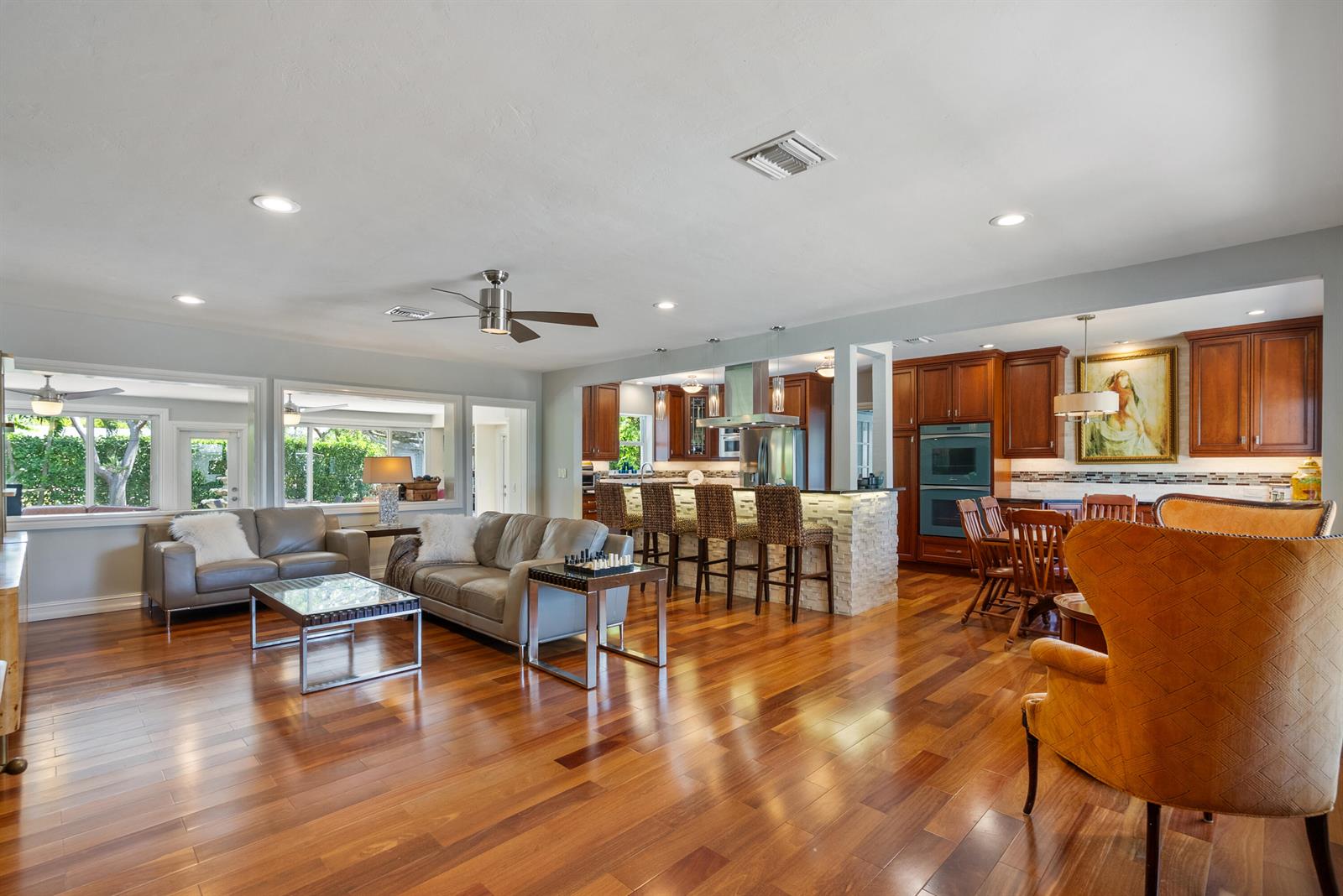 An open-concept living and dining area features hardwood floors, a kitchen island, and leather furniture — 145 Vassar Drive, FL 33460, FL