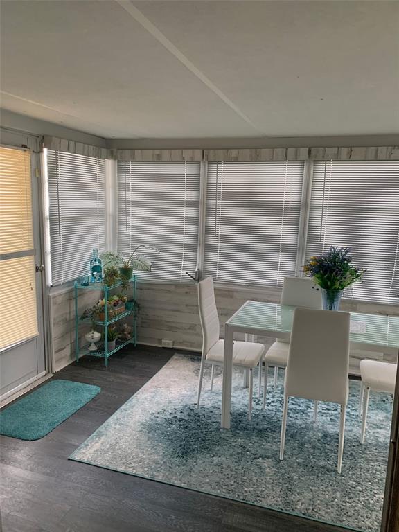 A sunroom features a dining table, white chairs, a blue rug, and horizontal window blinds — 2341 BARON DRIVE, HOLIDAY, FL