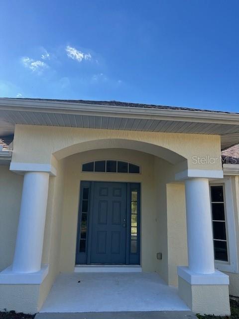 The front entrance of a house features a blue door, two white columns, and an archway — 2447 JARVIS STREET, NORTH PORT, FL