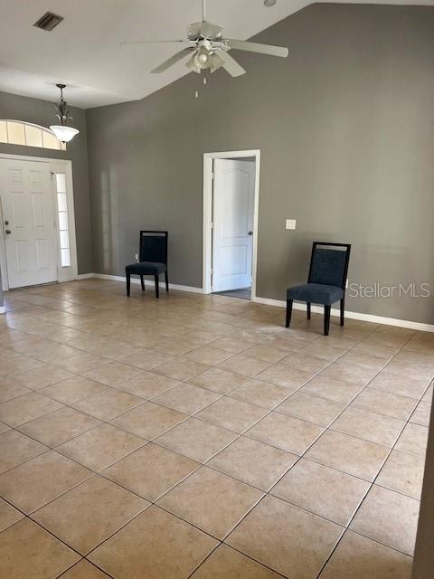 An empty room with beige tile flooring, gray walls, a ceiling fan, and two chairs — 2447 JARVIS STREET, NORTH PORT, FL