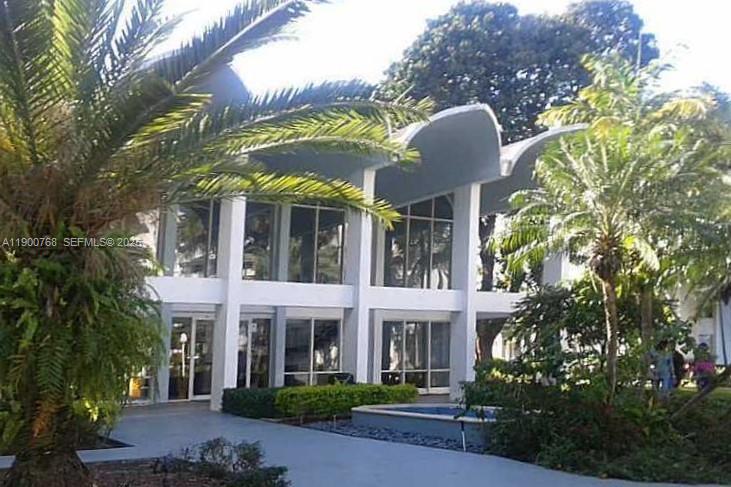 A two-story building with a distinctive scalloped roofline, large windows, and surrounding palm trees — 494 NW 165th St Rd # 602, Miami FL 33169, MIAMI, FL
