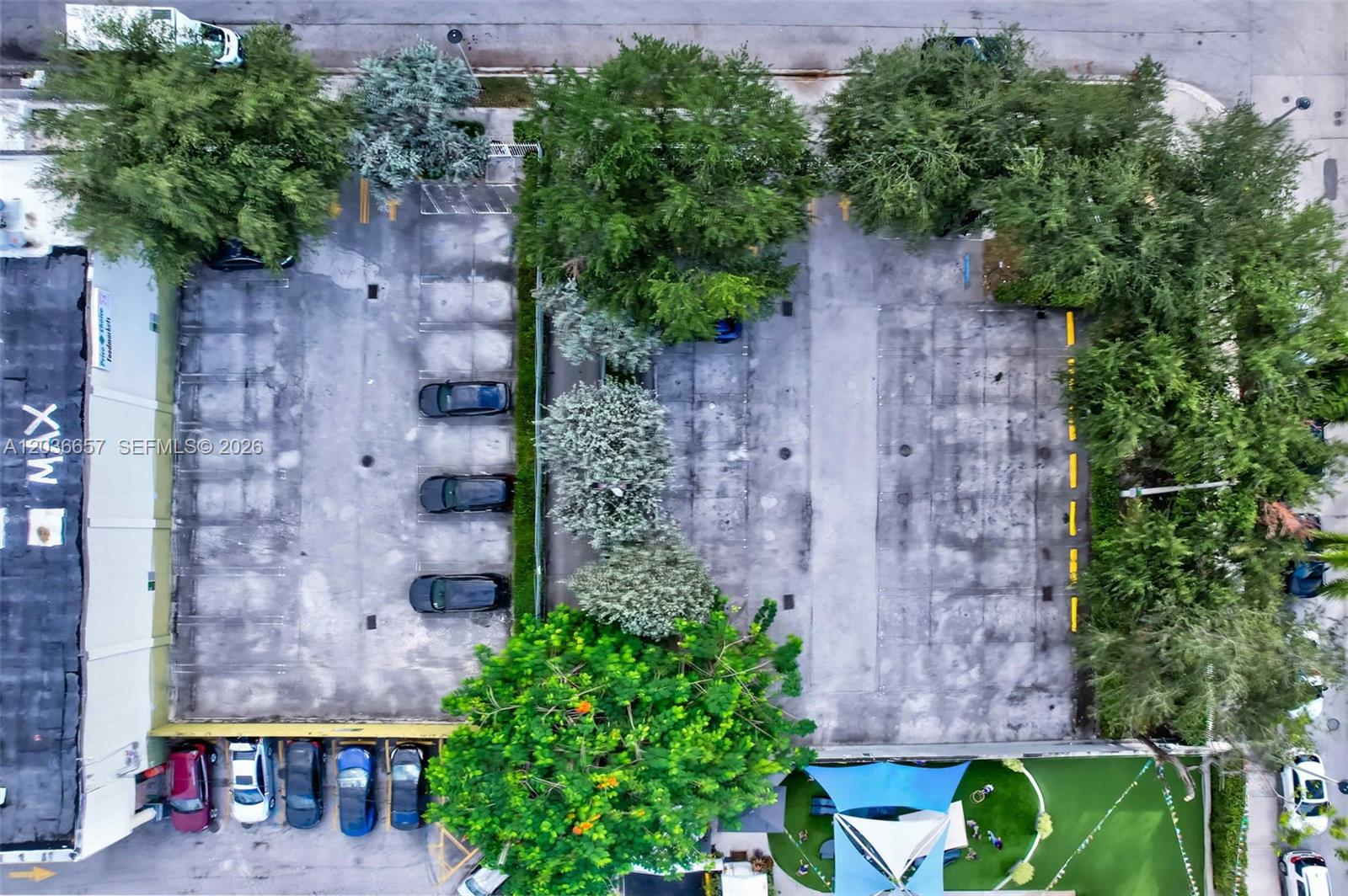 An aerial view shows a paved parking lot with several parked cars and surrounding trees — 275 NE 18th St, Miami FL 33132, MIAMI, FL