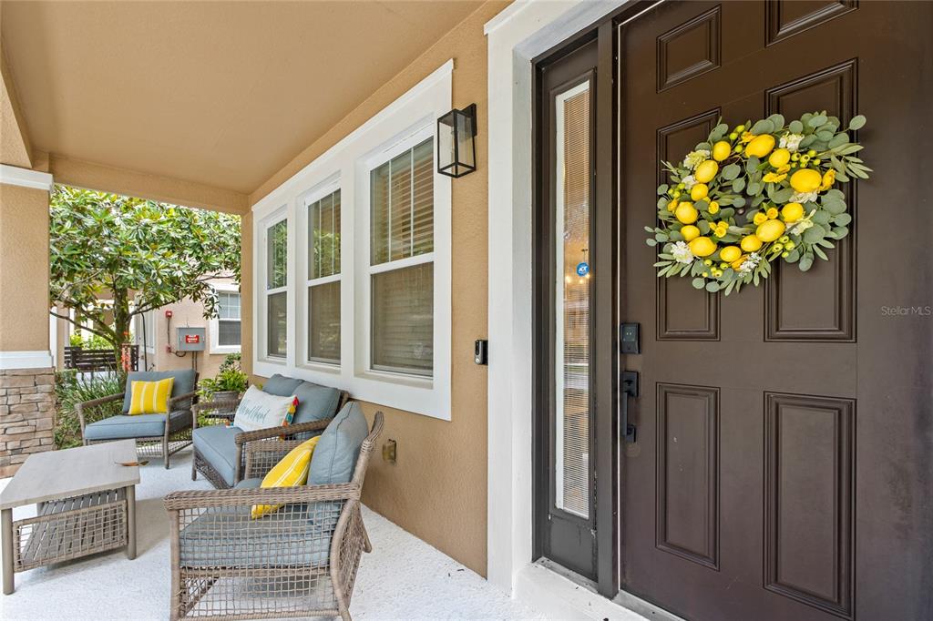 A covered front porch features wicker seating, a lemon wreath on the door, and windows — 7951 NORTHLAKE PARKWAY, ORLANDO, FL