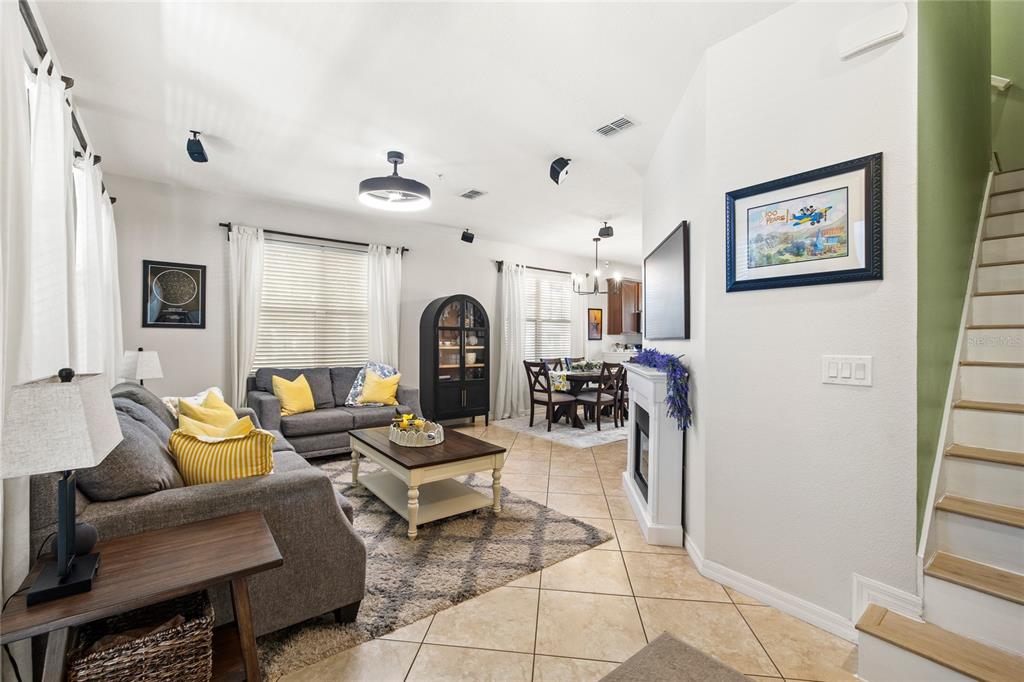 A living room with tile floors, a fireplace, and an adjacent dining area and staircase — 7951 NORTHLAKE PARKWAY, ORLANDO, FL