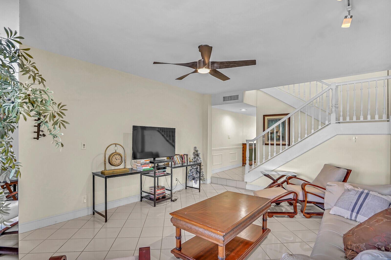A living room features tile flooring, a wooden coffee table, a staircase, and a ceiling fan — 584 SE 20th Avenue # 2, Deerfield Beach FL 33441, DEERFIELD BEACH, FL