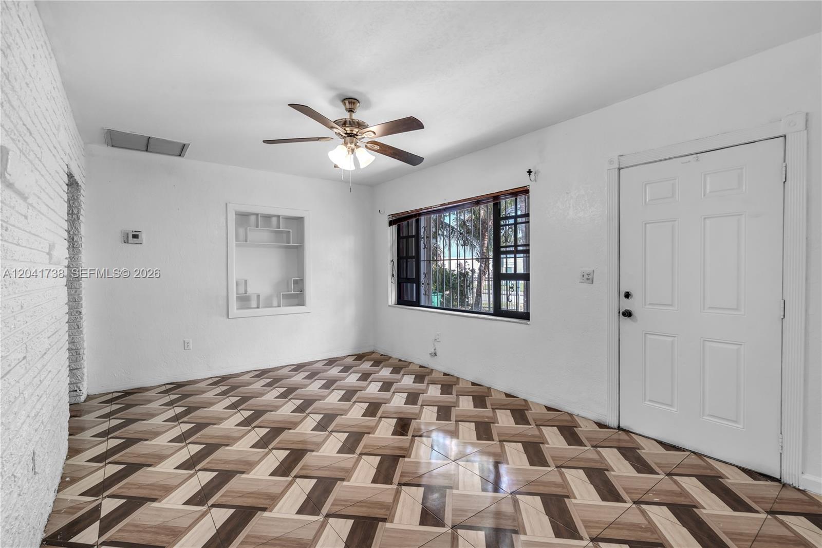 A room with white walls, a ceiling fan, a built-in shelf, and patterned tile flooring — 576 NW 147th St, Miami FL 33168, MIAMI, FL