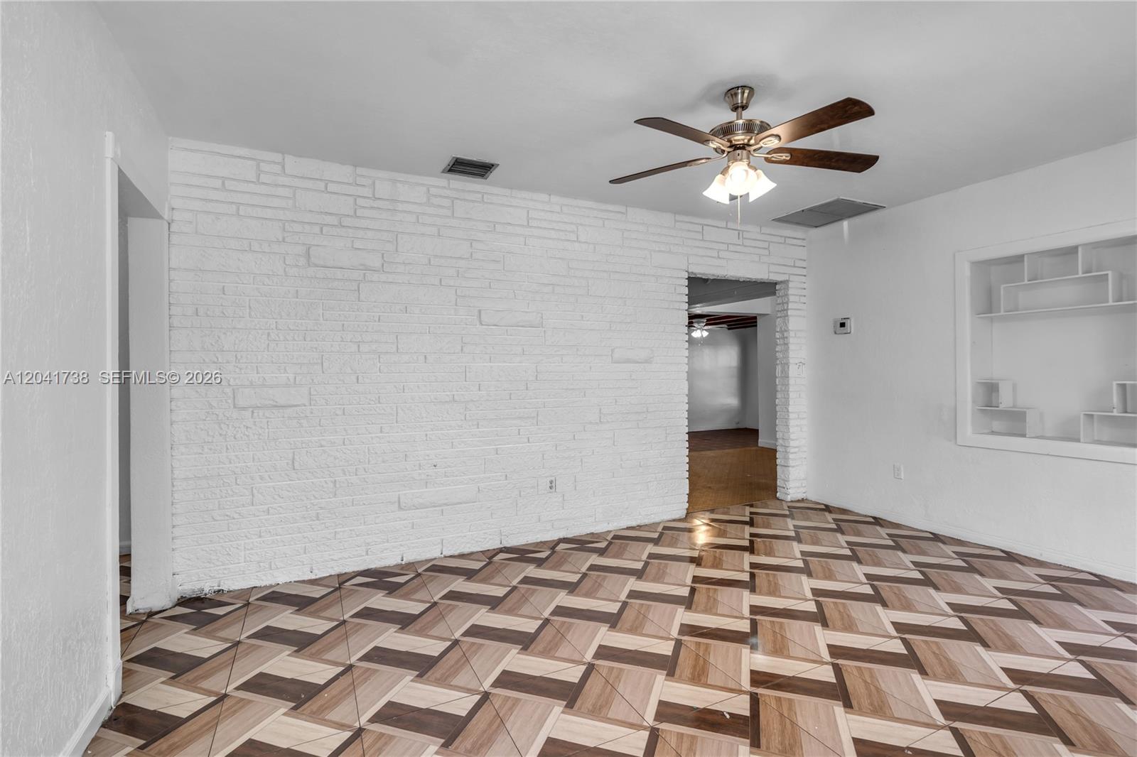 A room with a white brick accent wall, patterned tile flooring, and a ceiling fan — 576 NW 147th St, Miami FL 33168, MIAMI, FL