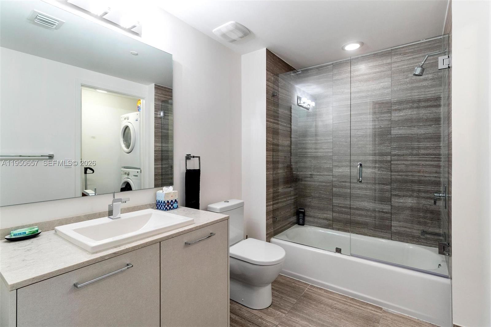 A modern bathroom features a vanity, a toilet, and a glass-enclosed tub with tiled walls — 1010 Brickell Ave # 1404, Miami FL 33131, MIAMI, FL