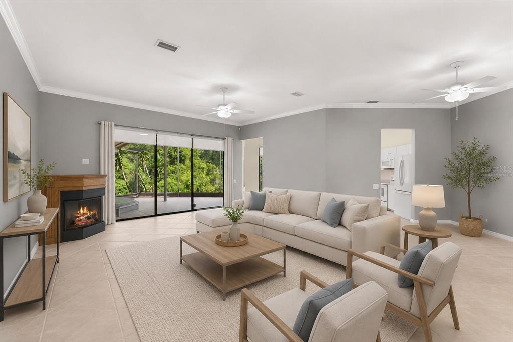 A living room with a fireplace, sectional sofa, two armchairs, and sliding glass doors — 4201 WATERSCAPE DRIVE, PALM HARBOR, FL