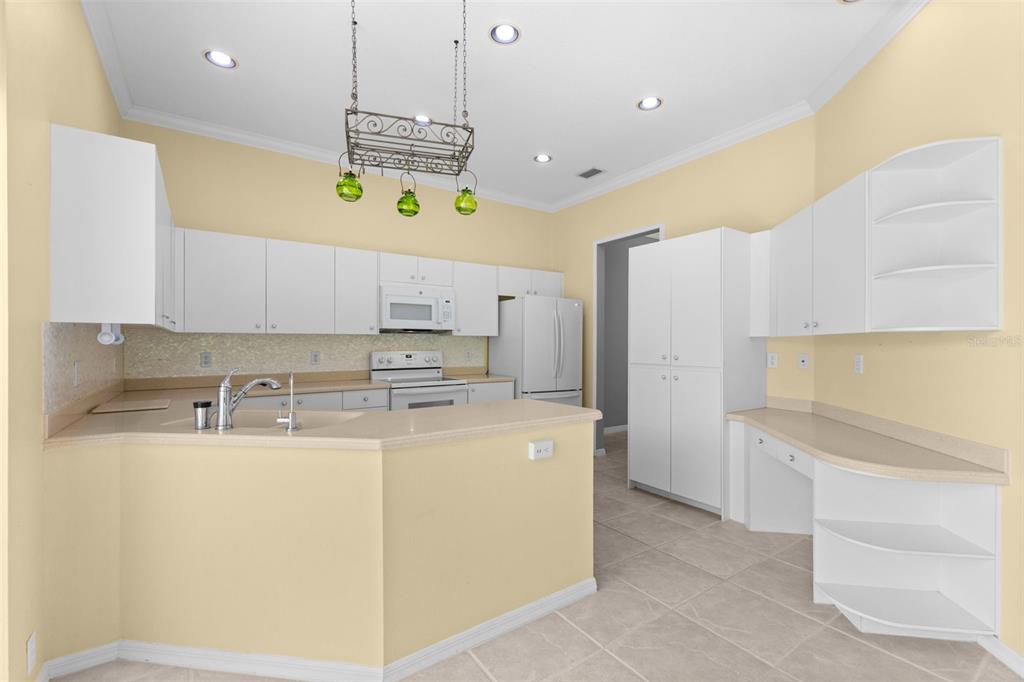 A kitchen features white cabinets, light countertops, a breakfast bar, and a built-in desk area — 4201 WATERSCAPE DRIVE, PALM HARBOR, FL