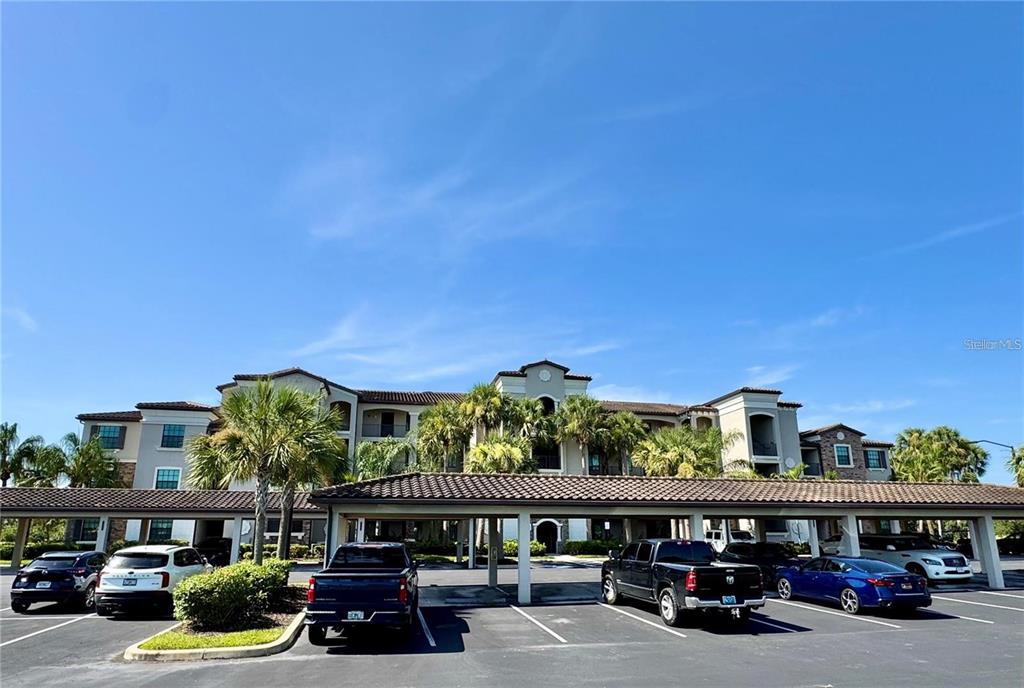 A multi-story apartment building with a covered parking area in the foreground — 16706 VARDON TERRACE UNIT 104, BRADENTON, FL