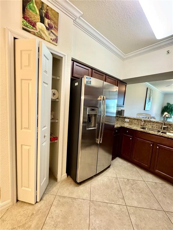 A kitchen features stainless steel appliances, dark wood cabinets, and a pantry with folding doors — 16706 VARDON TERRACE UNIT 104, BRADENTON, FL
