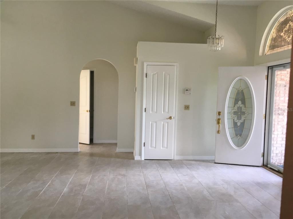 An interior view of an entryway with tiled floors, a white door, and an arched doorway — 1912 FAYETTEVILLE AVENUE, DELTONA, FL
