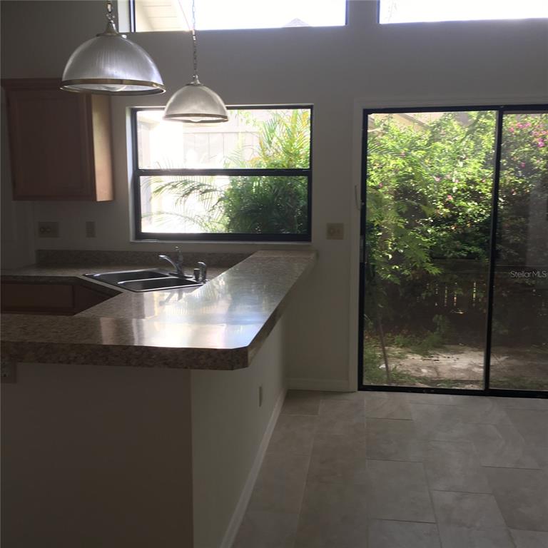 A kitchen features a granite breakfast bar, stainless steel sink, and sliding glass patio doors — 1912 FAYETTEVILLE AVENUE, DELTONA, FL