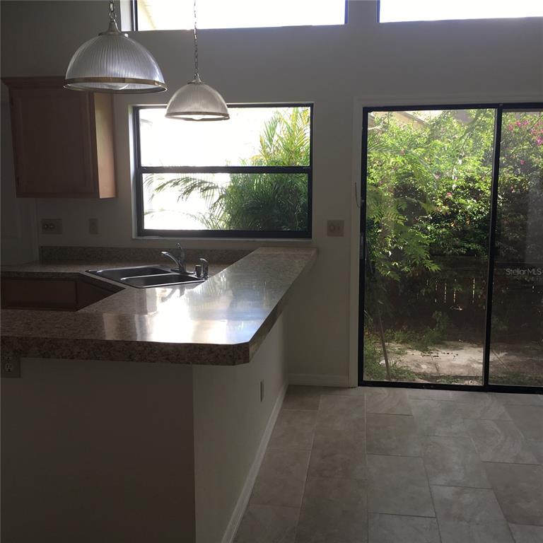 A kitchen with a granite breakfast bar, pendant lights, and a sliding glass door — 1912 FAYETTEVILLE AVENUE, DELTONA, FL