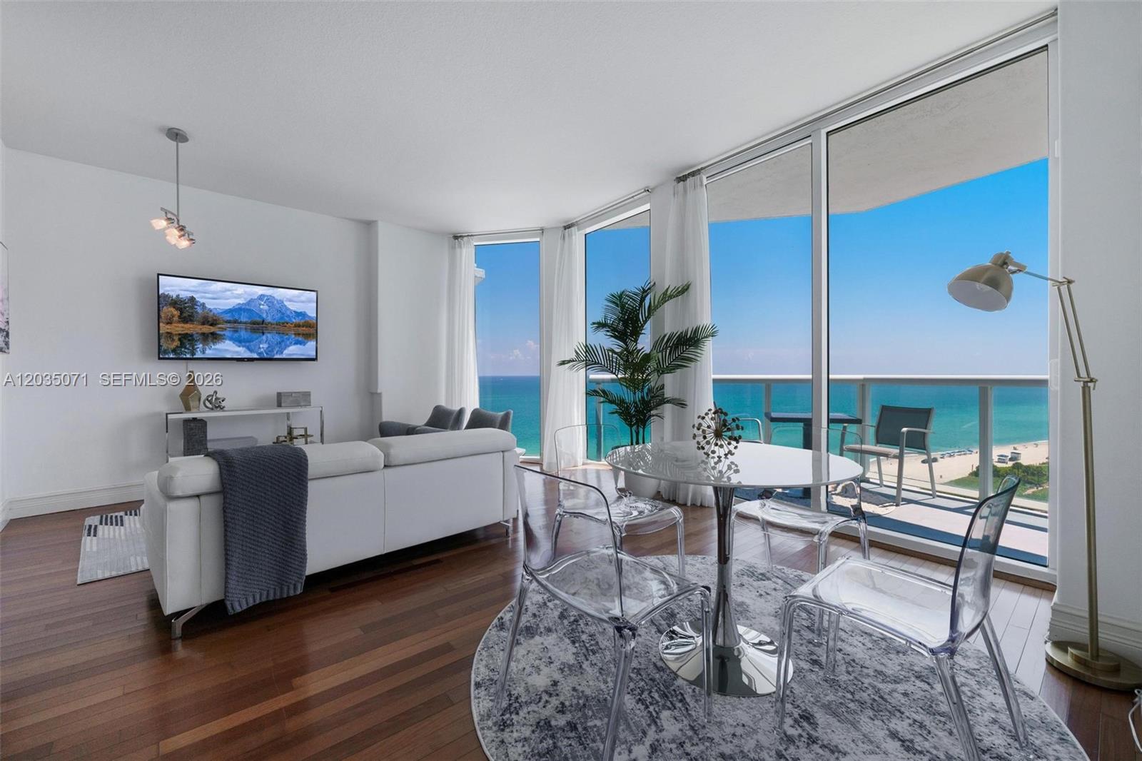 A living and dining area features floor-to-ceiling windows with ocean views and hardwood floors — 6515 Collins Ave # 1405, Miami Beach FL 33141, MIAMI BEACH, FL