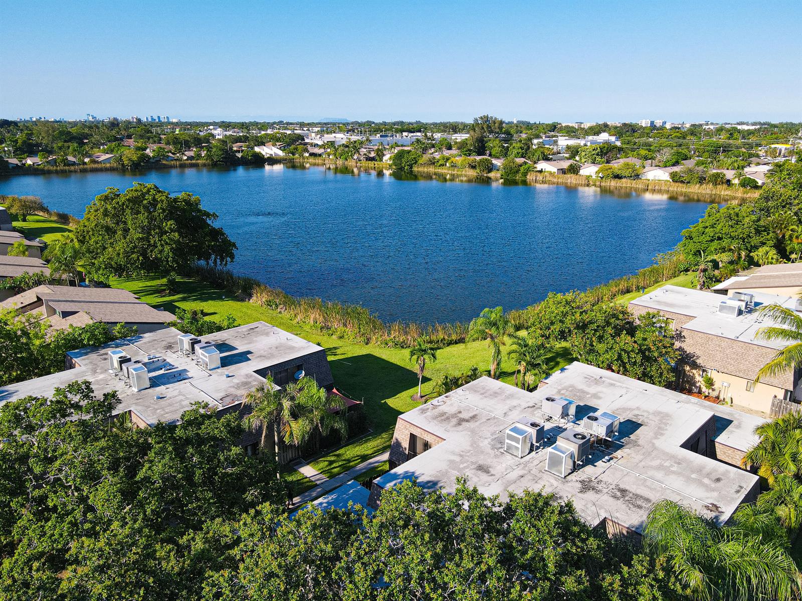 An aerial view of residential buildings with flat roofs situated beside a large lake — 4702 Waterview Circle, Palm Springs FL 33461, PALM SPRINGS, FL