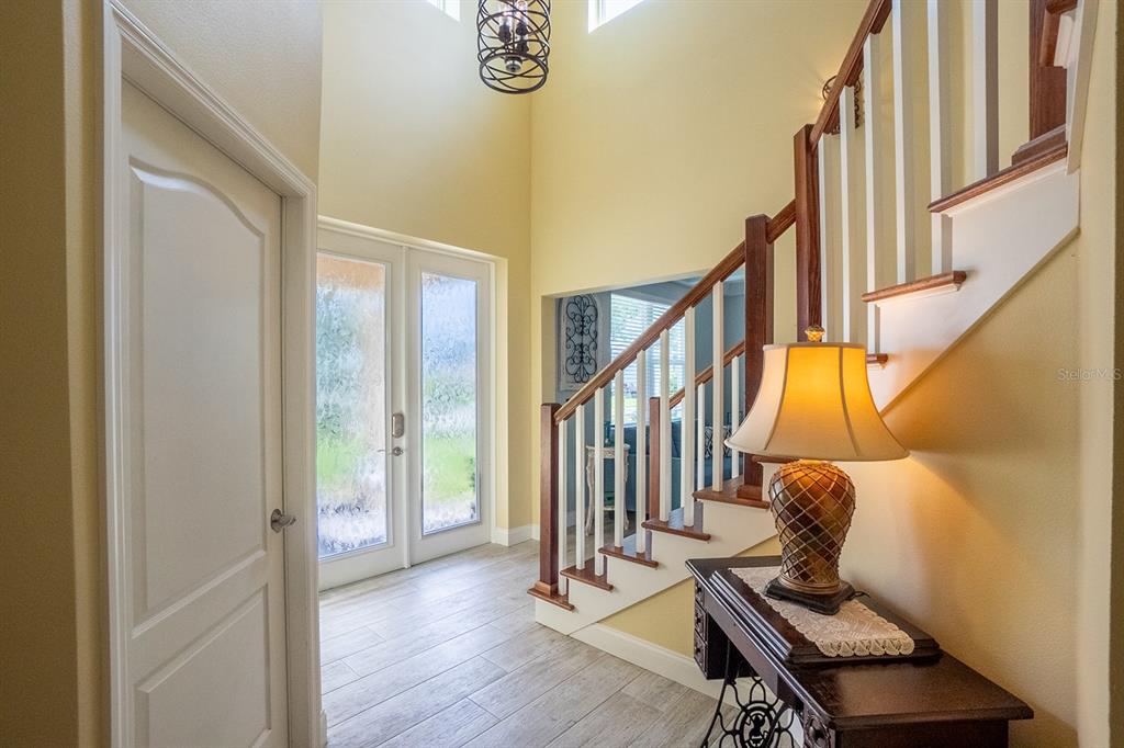 An entryway features a staircase with wooden railings, a chandelier, and a console table — 590 SHEARWOOD DRIVE, FLAGLER BEACH, FL