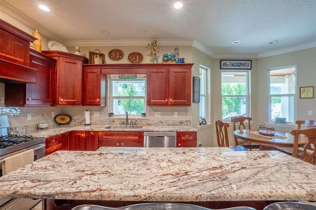 A kitchen features cherry wood cabinets, granite countertops, a large island, and a dining area — 590 SHEARWOOD DRIVE, FLAGLER BEACH, FL