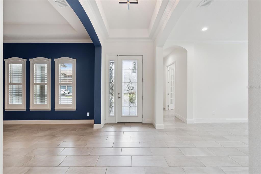 An entryway with light tile flooring, a dark blue accent wall, and a glass-paneled front door — 1417 OIL LAMP COVE, LAKE MARY, FL