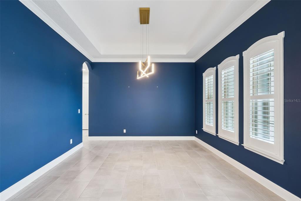 A dining room features deep blue walls, a dark wood table, and light-colored upholstered chairs — 1417 OIL LAMP COVE, LAKE MARY, FL