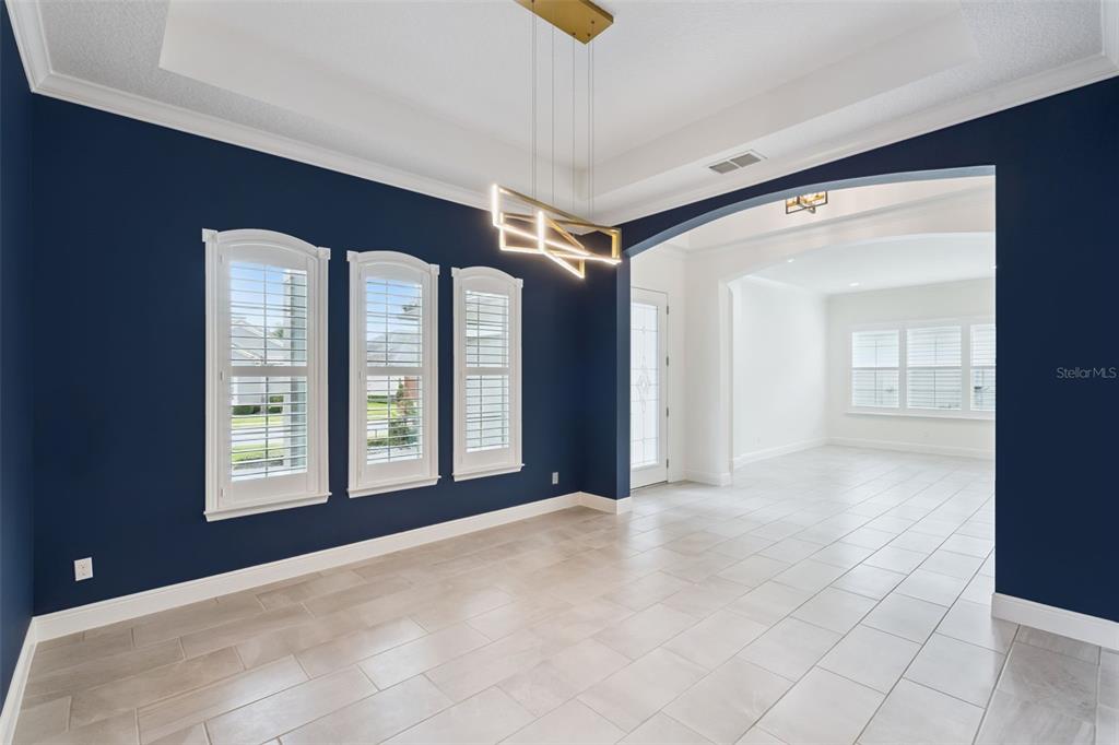 A dining room with navy blue walls, a tray ceiling, modern chandelier, and tile flooring — 1417 OIL LAMP COVE, LAKE MARY, FL