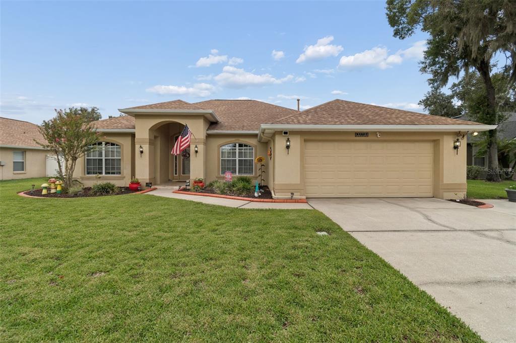 A single-story suburban house with a tan stucco exterior, a two-car garage, and a lawn — 3119 BLACKWATER OAKS WAY, MULBERRY, FL