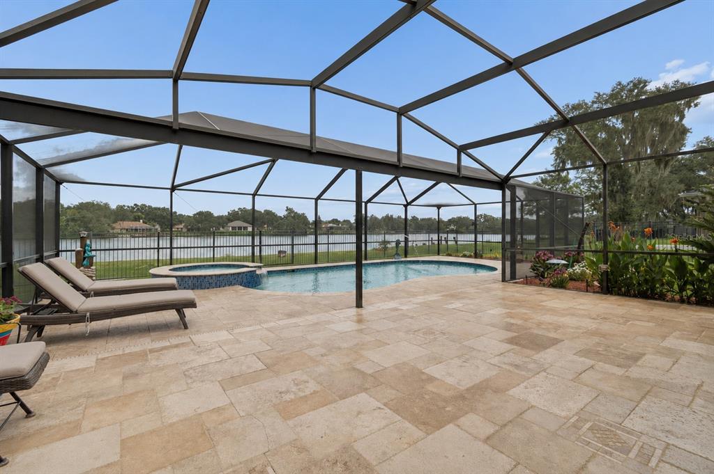 A screened-in patio features a swimming pool, a hot tub, and stone tile flooring — 3119 BLACKWATER OAKS WAY, MULBERRY, FL