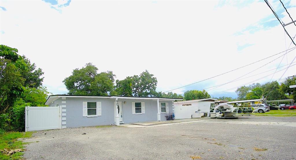 A single-story gray house with a gravel driveway and a white fence — 601 LIME TREE ROAD, TAMPA, FL