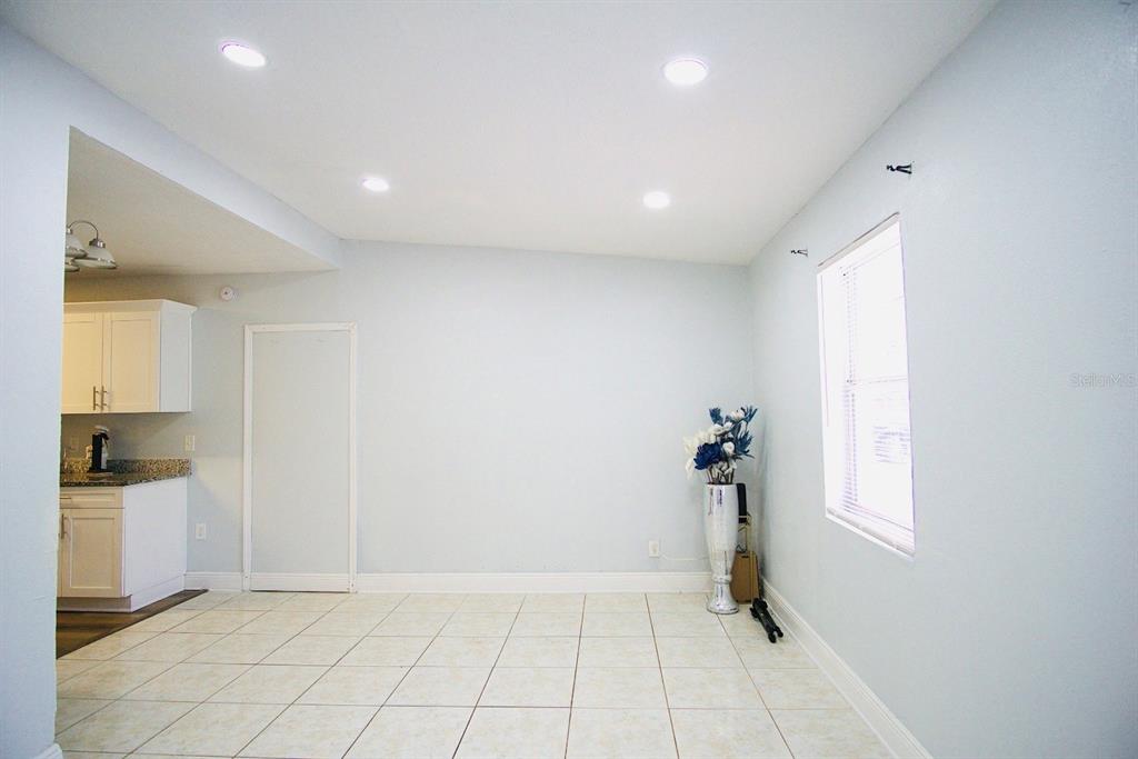 A dining area with light-colored tile flooring, recessed lighting, and a window on the right — 601 LIME TREE ROAD, TAMPA, FL