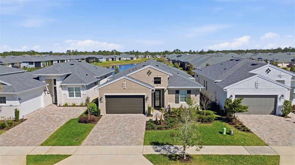 An aerial view shows a tan single-story house with a dark garage between two neighbors — 899 MEGANO BOULEVARD, DELAND, FL