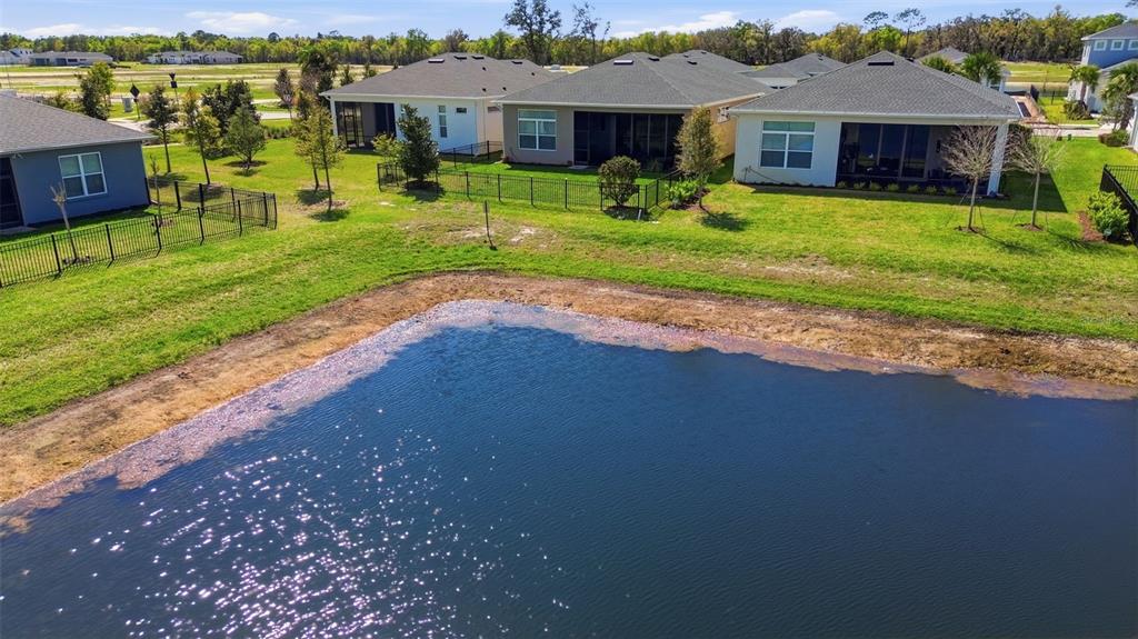 An aerial view shows a pond in front of several suburban houses with fenced backyards — 899 MEGANO BOULEVARD, DELAND, FL