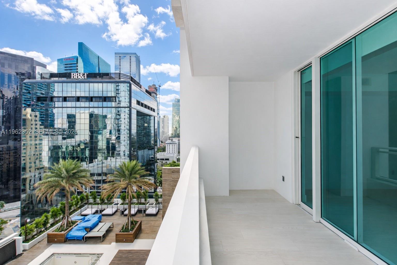 A modern balcony with light tile flooring overlooks a city skyline and a pool deck — 1080 Brickell Ave # 1706, Miami FL 33131, MIAMI, FL