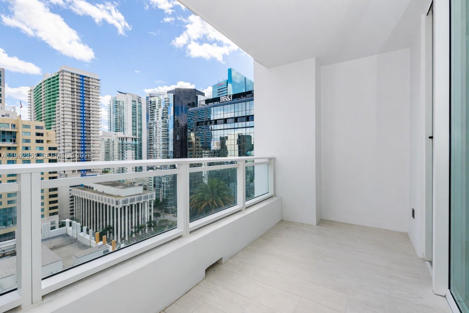 A modern balcony with white tile flooring and a glass railing overlooking a city skyline — 1080 Brickell Ave # 1706, Miami FL 33131, MIAMI, FL