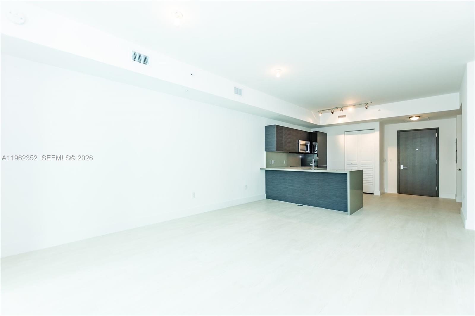 An open-concept room features a kitchen with dark cabinetry and a central island — 1080 Brickell Ave # 1706, Miami FL 33131, MIAMI, FL