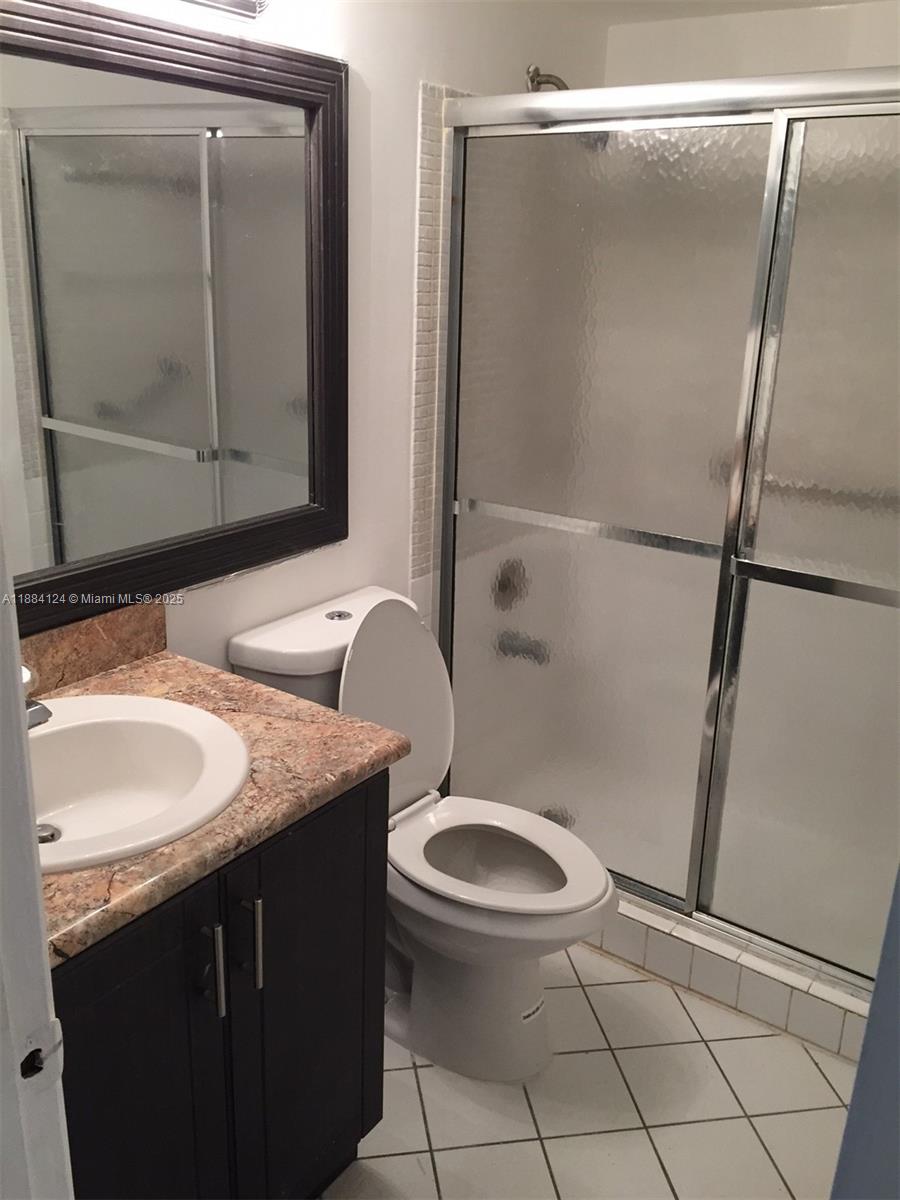 A bathroom features a dark vanity with a stone countertop, a toilet, and a shower — 182 Markham I # 182, Deerfield Beach FL 33442, DEERFIELD BEACH, FL