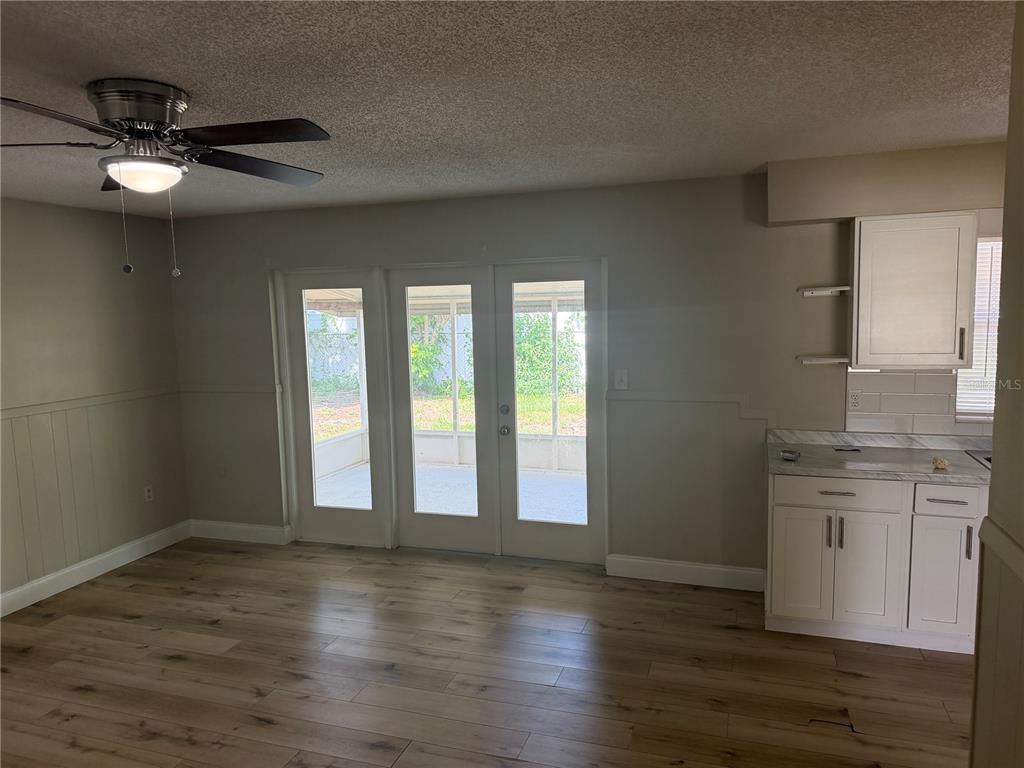 A room with wood-look flooring, a ceiling fan, white cabinets, and glass doors to a patio — 4518 GASPARILLA AVENUE, ORLANDO, FL