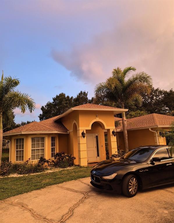 A single-story yellow stucco house with a tiled roof and a black car parked outside — 4856 ARCHIE LANE, FORT MYERS, FL