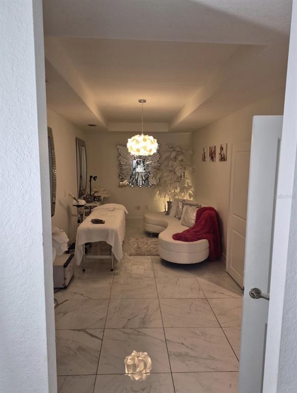 A spa room features a treatment table, curved white sofa, and white marble-look tile flooring — 4856 ARCHIE LANE, FORT MYERS, FL