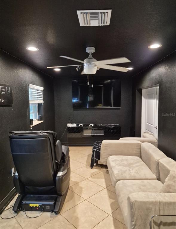 A media room features black walls, a white ceiling fan, a television, and light-colored seating — 4856 ARCHIE LANE, FORT MYERS, FL